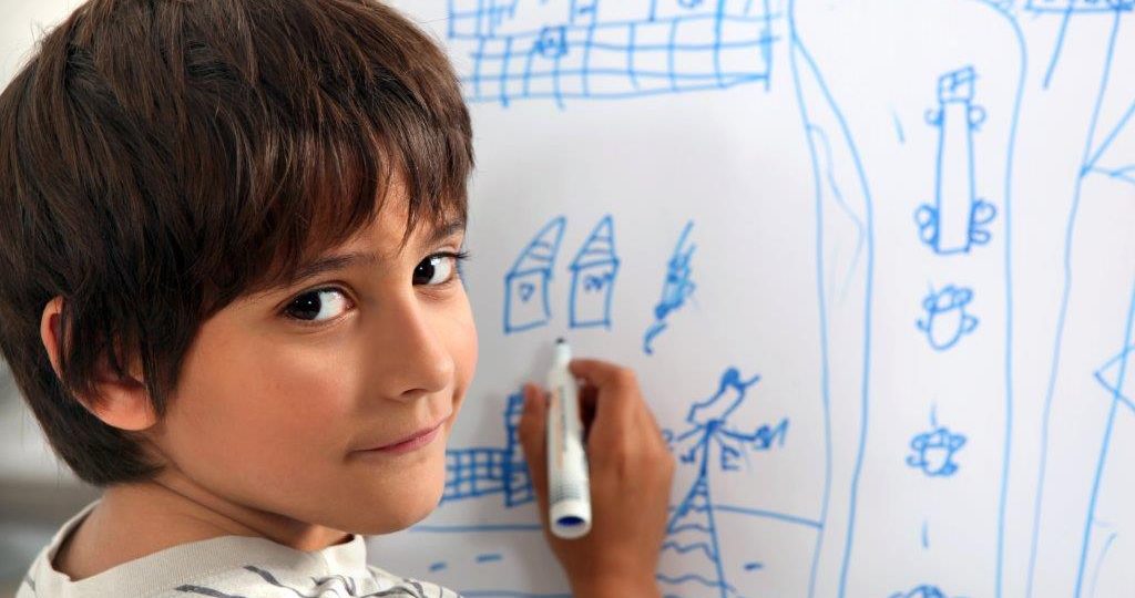 Young boy drawing on a white board